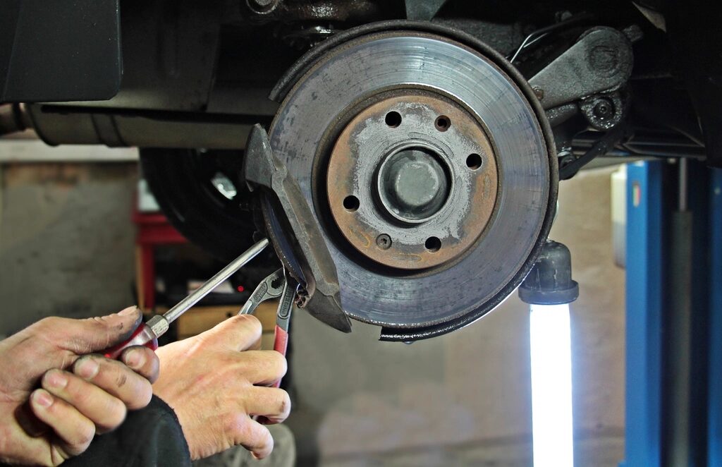 Hands checking a brake assembly on the lift