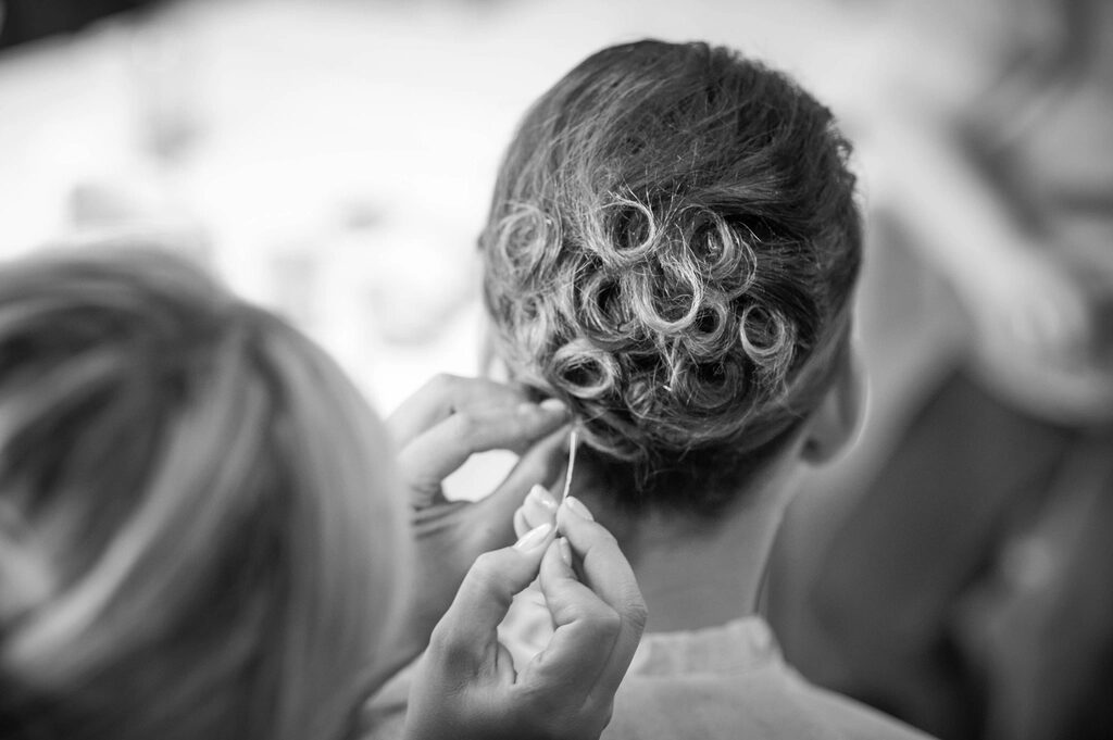 Stylist pinning curls into a bridal updo, black and white