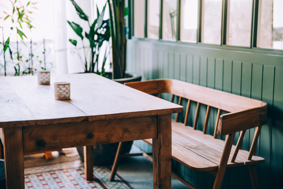 Wood dining table and bench by a bright window