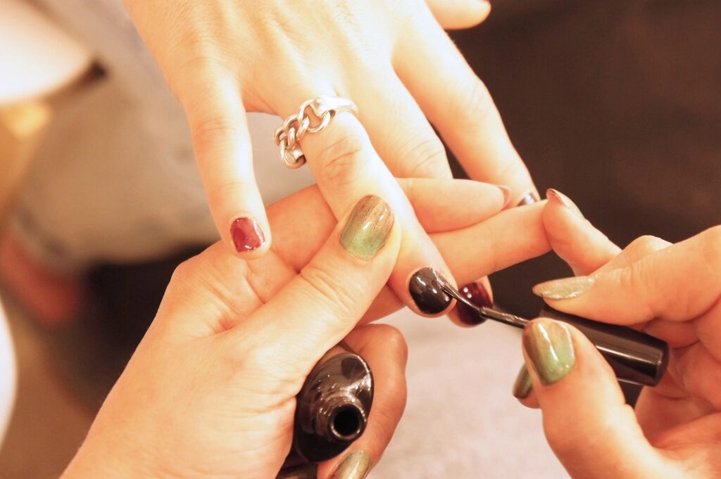 Technician applying dark polish to a client's nails