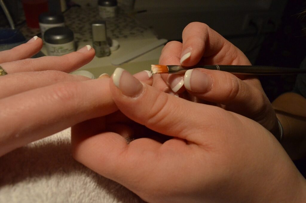 Brush painting a French tip on a natural nail