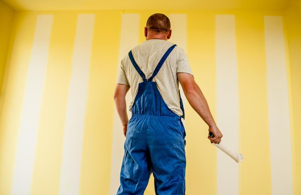 Painter rolling pale paint onto an interior wall
