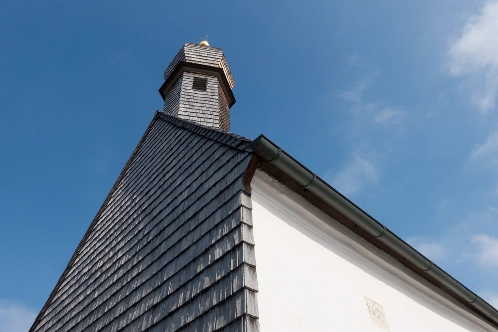 A finished shingle gable and turret against a blue sky